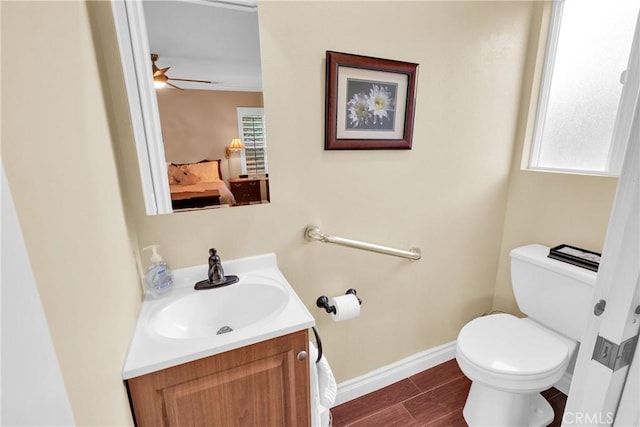 bathroom with baseboards, a ceiling fan, toilet, wood finished floors, and vanity