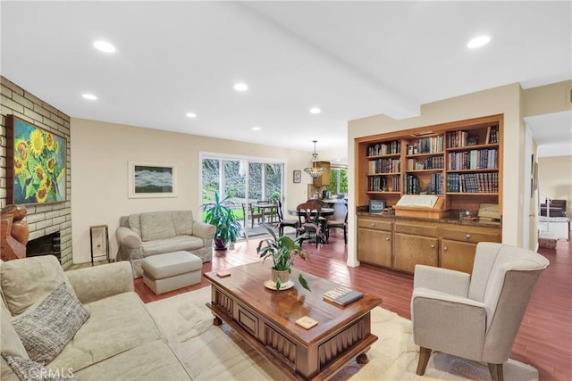 living room with light wood-style floors, recessed lighting, and a brick fireplace