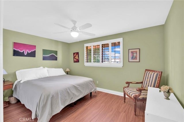 bedroom with ceiling fan, wood finished floors, and baseboards