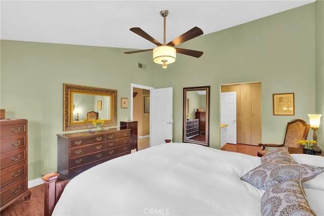 bedroom with baseboards, visible vents, ceiling fan, wood finished floors, and high vaulted ceiling