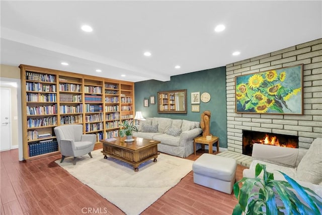 sitting room featuring a fireplace, wood finished floors, beam ceiling, and recessed lighting