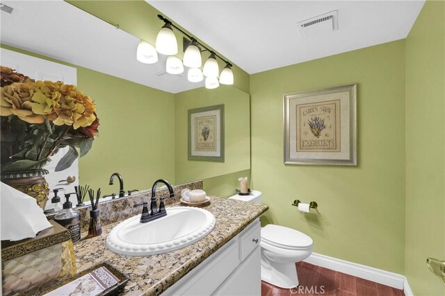 bathroom featuring baseboards, visible vents, toilet, wood finished floors, and vanity