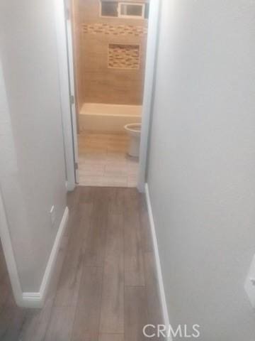 hall with baseboards and wood finished floors