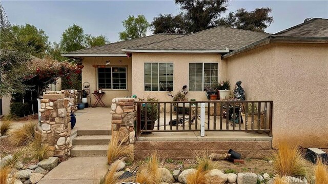 back of house with a shingled roof and stucco siding
