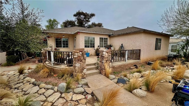 view of front of property featuring stucco siding and roof with shingles