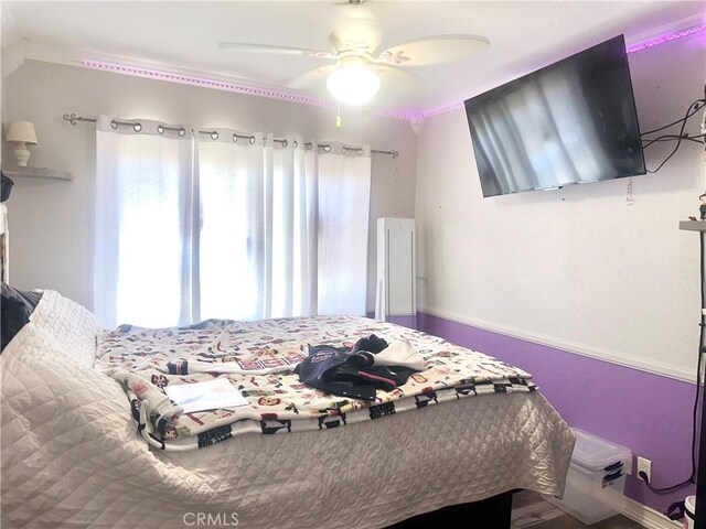 bedroom featuring ceiling fan, baseboards, and multiple windows