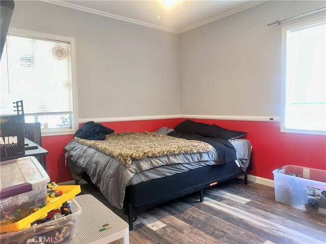 bedroom with multiple windows, baseboards, wood finished floors, and crown molding