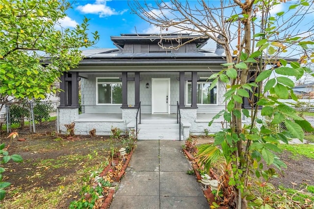 bungalow with a gate, roof mounted solar panels, fence, and a porch