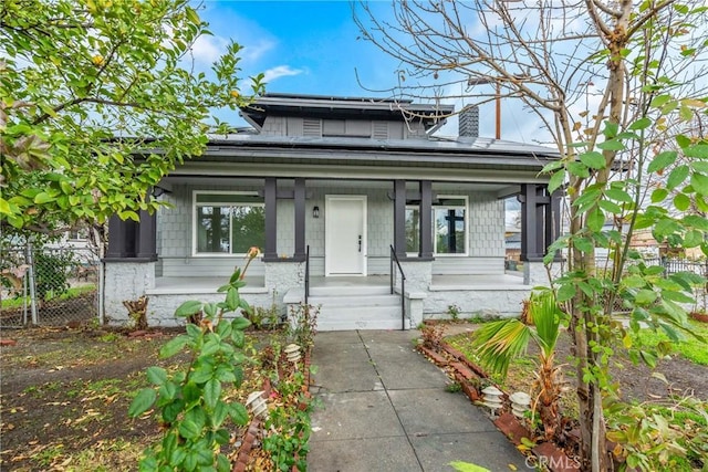 view of front of property with solar panels, a porch, and fence