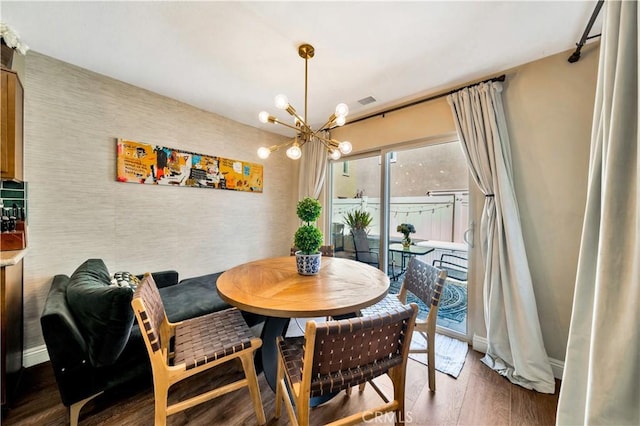 dining space featuring visible vents, a notable chandelier, wood finished floors, and baseboards