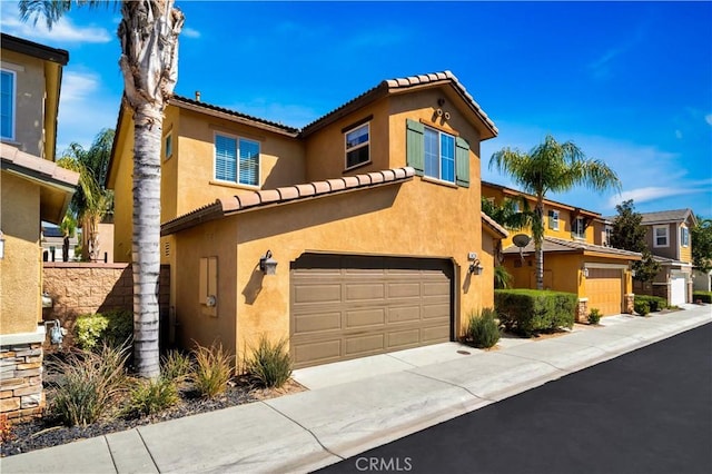 mediterranean / spanish home with a residential view, stucco siding, an attached garage, and driveway