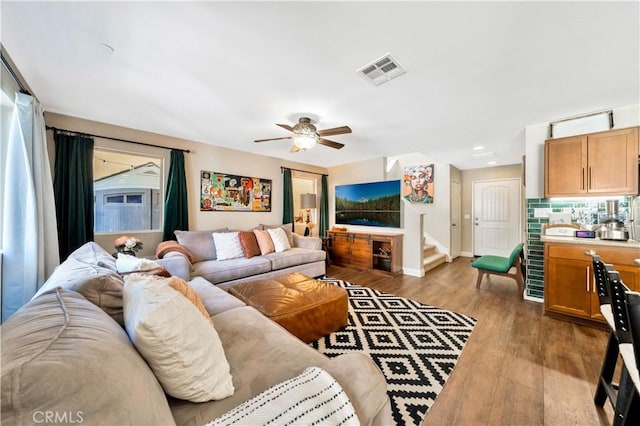 living room featuring visible vents, wood finished floors, baseboards, a healthy amount of sunlight, and stairs