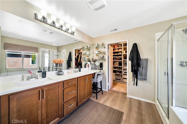 full bath featuring a sink, visible vents, wood finished floors, and a shower stall