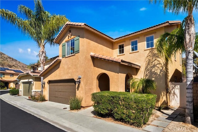 mediterranean / spanish home with fence, a garage, and stucco siding