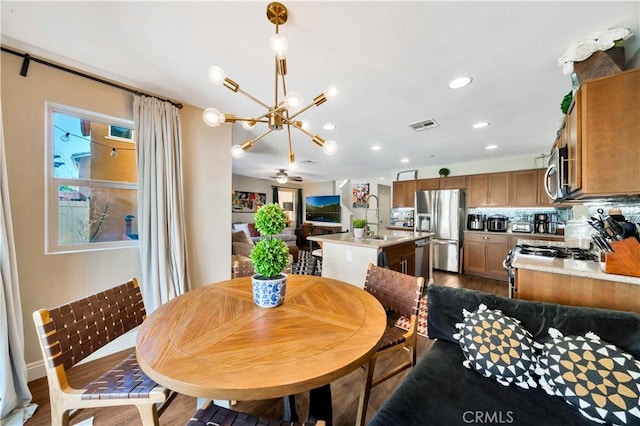 dining room with dark wood finished floors, ceiling fan with notable chandelier, recessed lighting, and visible vents