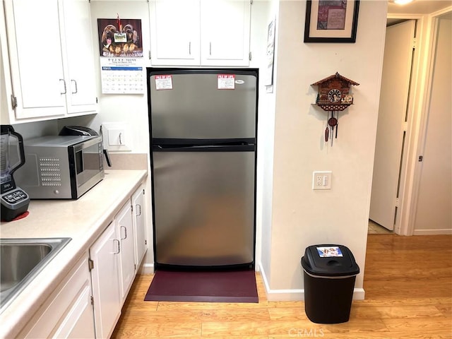 kitchen with a sink, stainless steel appliances, white cabinets, and light countertops