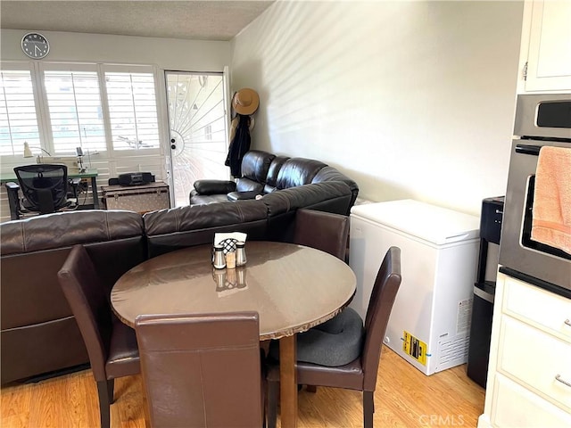 dining room with a textured ceiling and light wood-type flooring