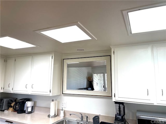 kitchen featuring white cabinets, light countertops, and a sink