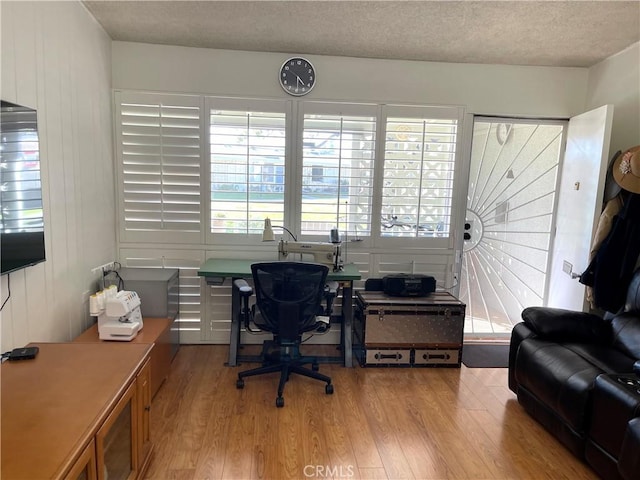 office with light wood finished floors and a textured ceiling