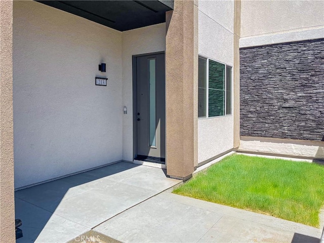 view of exterior entry with stone siding and stucco siding