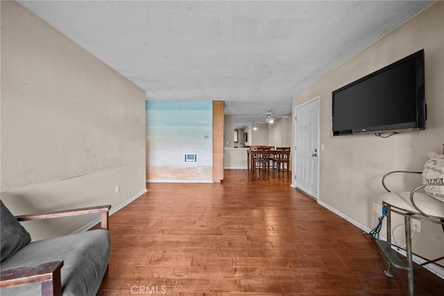 interior space with a textured ceiling, wood finished floors, and baseboards