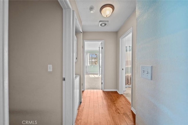 hall featuring light wood finished floors and baseboards