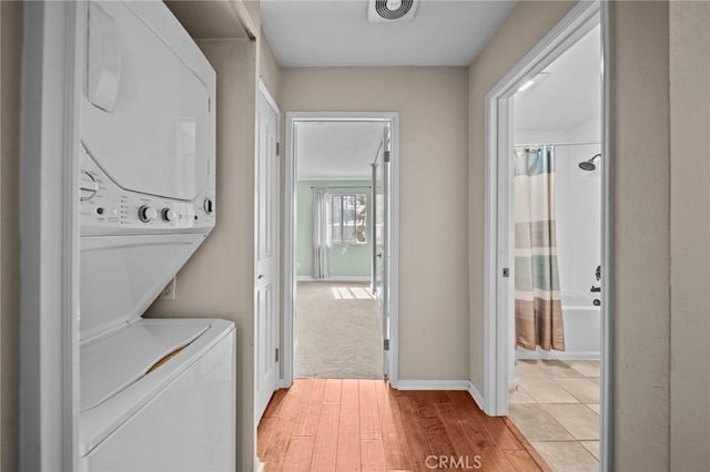 washroom with laundry area, visible vents, baseboards, light wood finished floors, and stacked washer and clothes dryer