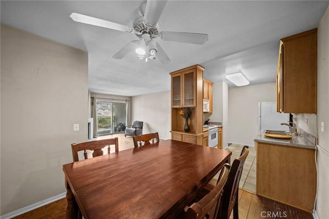 dining space with a ceiling fan, baseboards, and wood finished floors