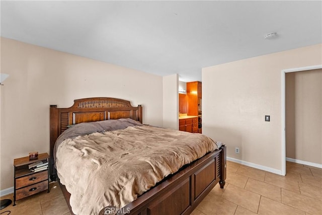 bedroom with light tile patterned floors, ensuite bathroom, and baseboards