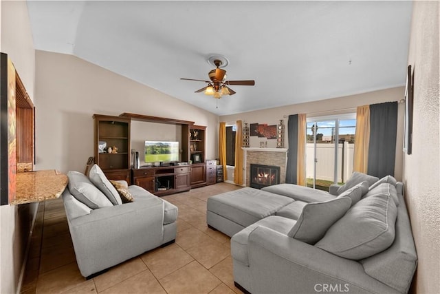 living area with vaulted ceiling, ceiling fan, light tile patterned flooring, and a glass covered fireplace