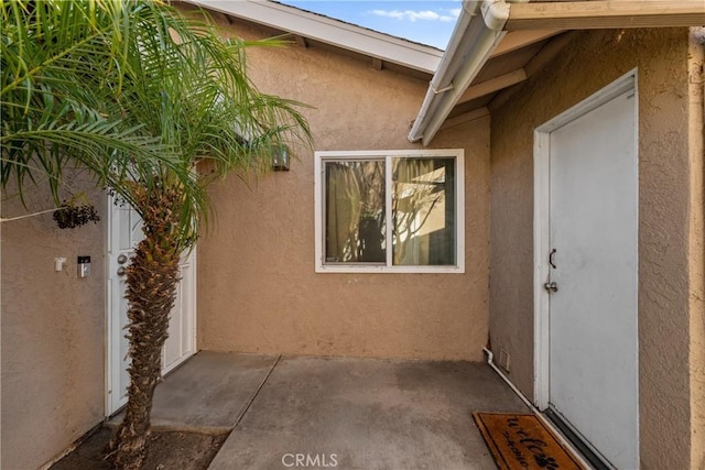 view of exterior entry featuring a patio and stucco siding