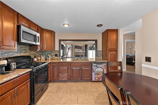 44680 La Paz Rd, Temecula, CA 92592 - kitchen featuring black range with gas stovetop, light stone counters, a sink, stainless steel microwave, and backsplash