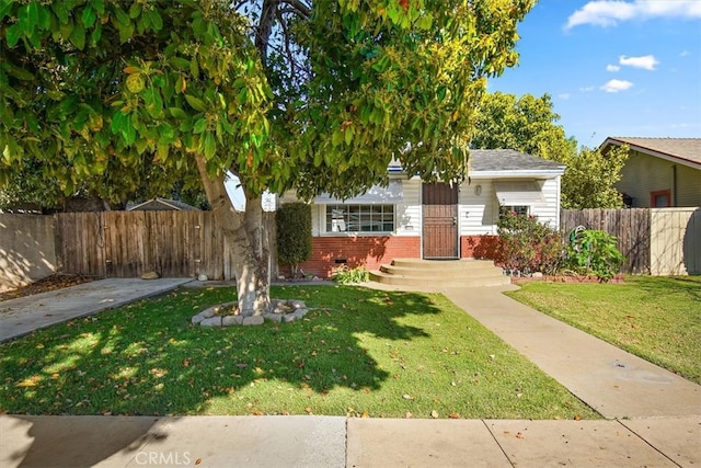 view of front facade featuring brick siding, fence, and a front lawn