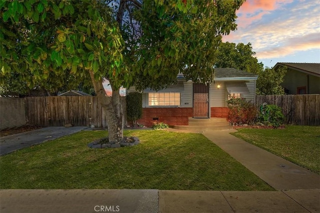 view of front facade with a front yard, brick siding, and fence