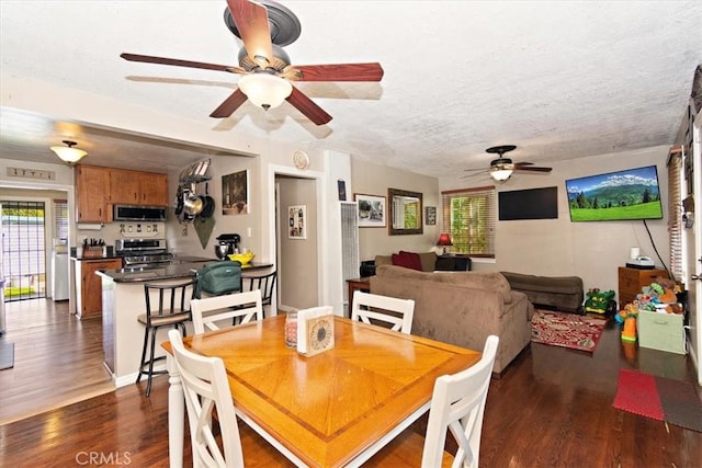 dining room with a ceiling fan, dark wood-style flooring, and a textured ceiling