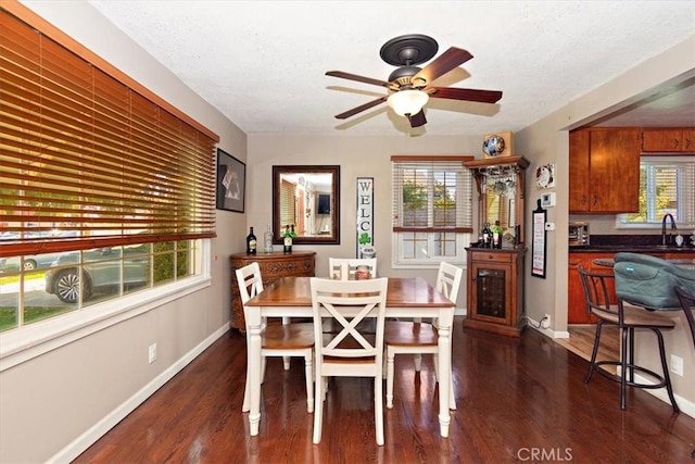 dining area featuring dark wood-style floors, a textured ceiling, baseboards, and a ceiling fan