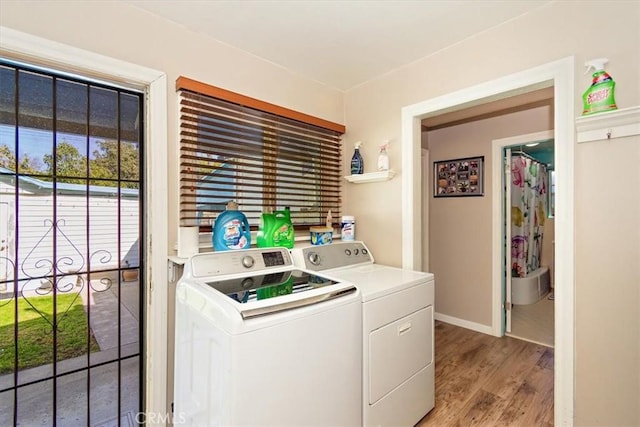 clothes washing area with light wood-type flooring, laundry area, independent washer and dryer, and baseboards