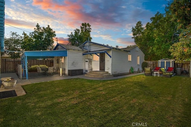 rear view of house featuring an outbuilding, a lawn, a patio area, and fence private yard