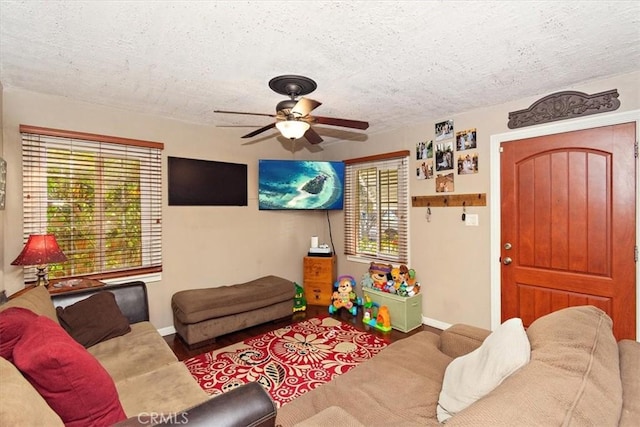 living room with a textured ceiling, ceiling fan, wood finished floors, and a wealth of natural light