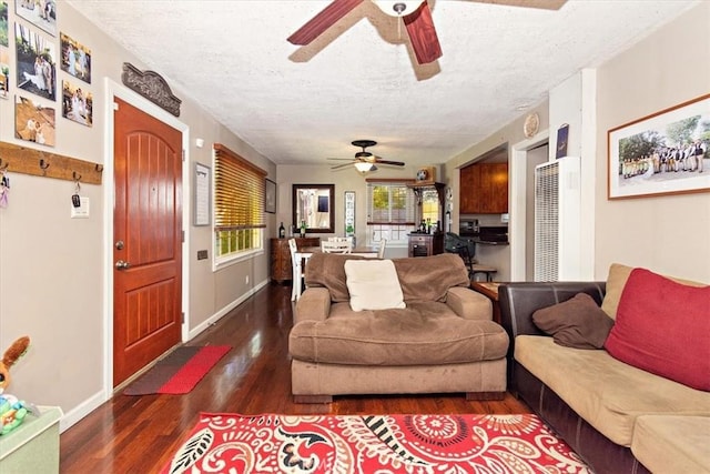 living room with a ceiling fan, a textured ceiling, baseboards, and wood finished floors