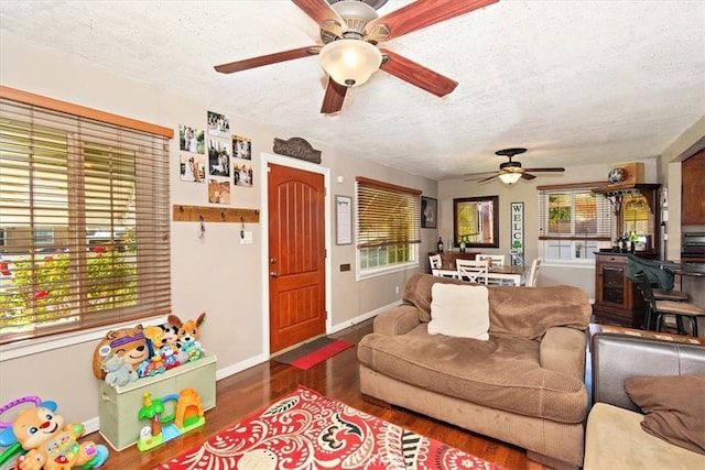 living room featuring ceiling fan, a textured ceiling, baseboards, and wood finished floors