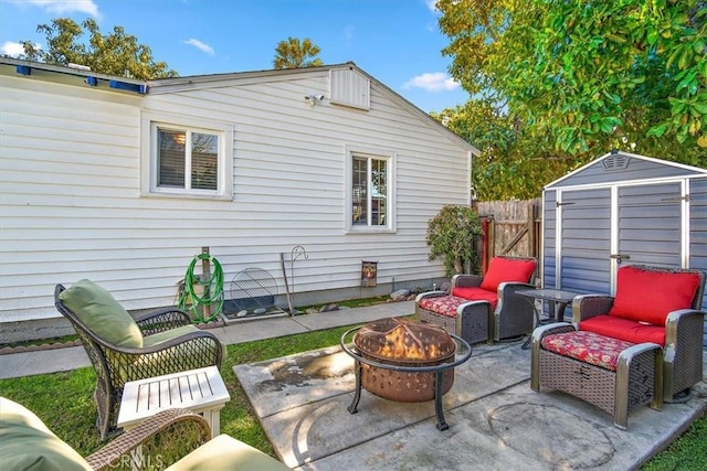 view of patio / terrace with an outbuilding, an outdoor living space with a fire pit, a storage unit, and fence