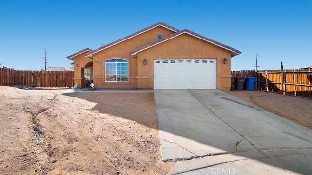 ranch-style home with an attached garage, driveway, fence, and stucco siding