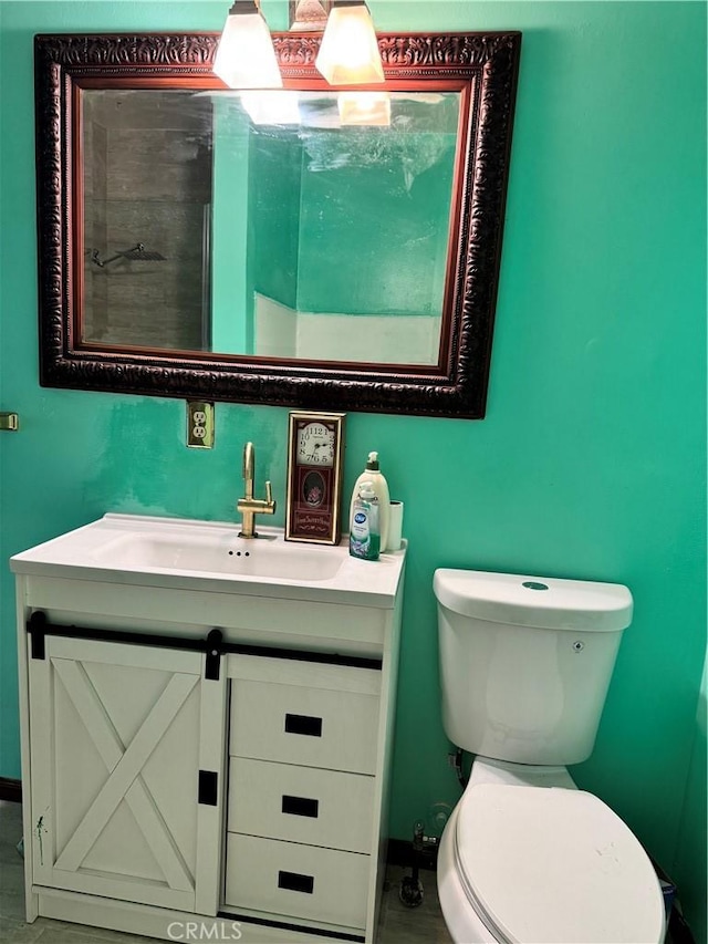 half bathroom with baseboards, vanity, and toilet