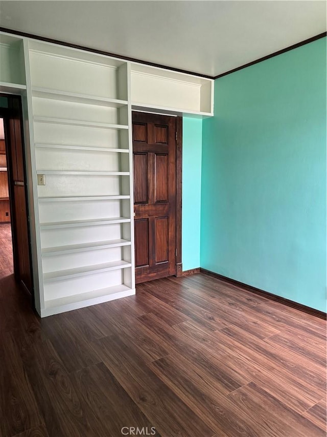 unfurnished bedroom with dark wood-style flooring and baseboards