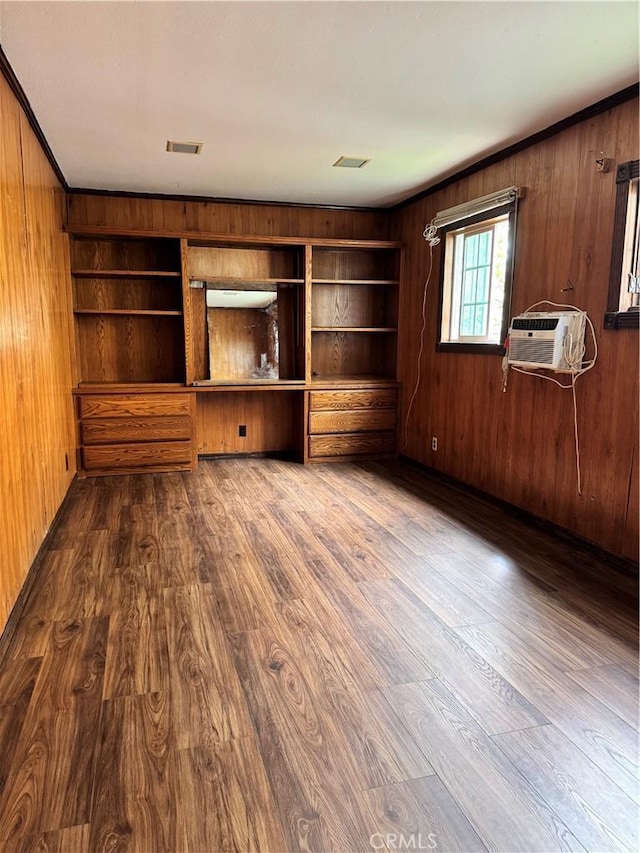 unfurnished living room with wood walls, dark wood-type flooring, and an AC wall unit