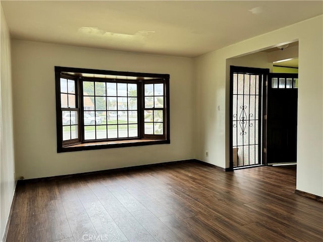 unfurnished room featuring dark wood-type flooring and baseboards