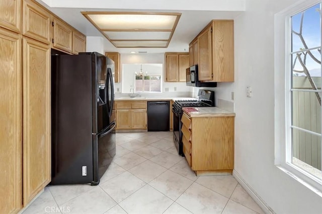 kitchen with light tile patterned floors, baseboards, a sink, black appliances, and light countertops