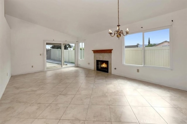 unfurnished living room with light tile patterned floors, lofted ceiling, a notable chandelier, and a tiled fireplace