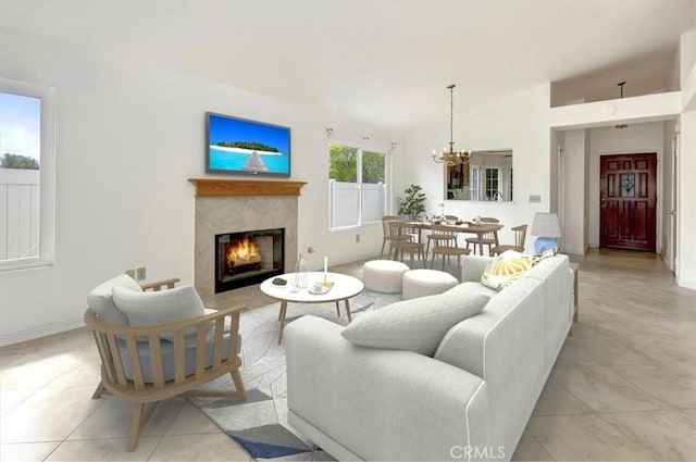 living room featuring baseboards, lofted ceiling, light tile patterned flooring, a high end fireplace, and a chandelier